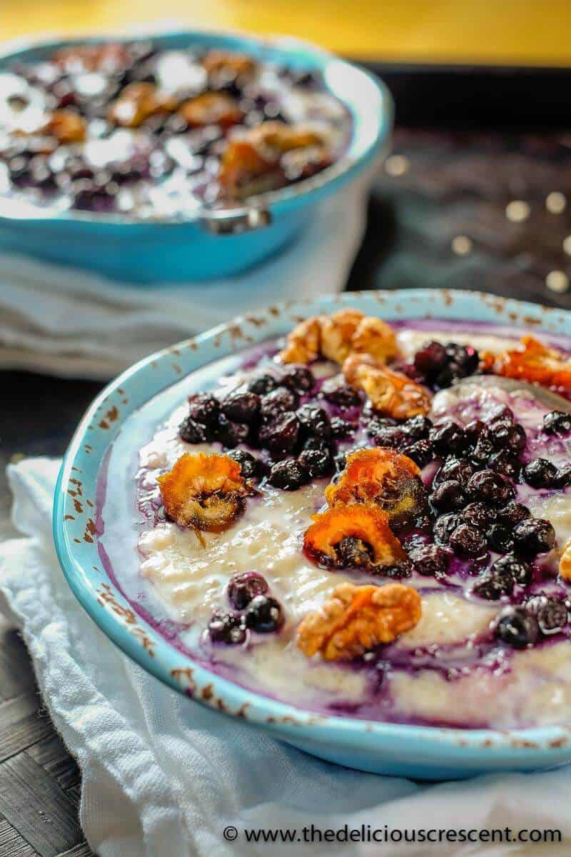 Barley porridge with blueberries, walnuts, dates and honey in a blue bowl