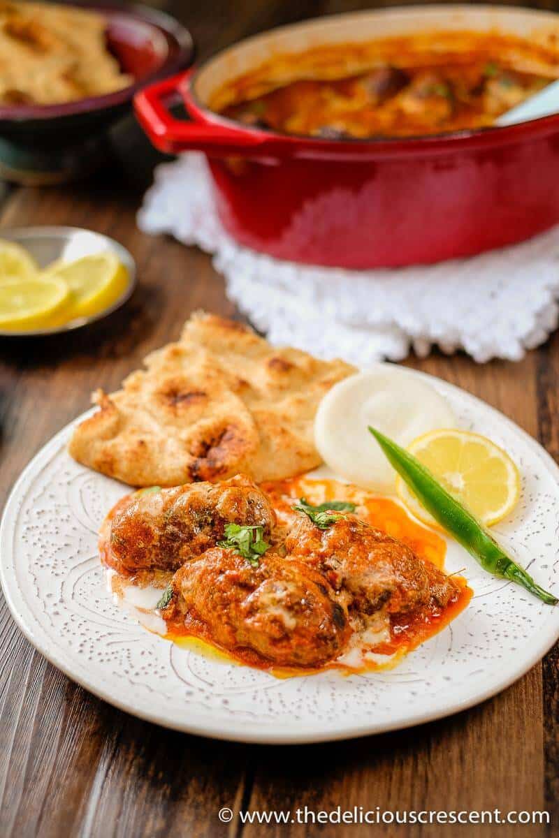 Kofta curry is a delicious dish of succulent grilled or broiled beef meatballs in a rich, creamy and spicy sauce. It is full of fragrant Indian spices and makes a great weeknight dinner. This easy low carb meatball curry recipe is also freezer friendly. Great tips for lightening up the sauce included. Make it with ground lamb or gluten free. #Indianfood #kofta #curry #beef Kofta Masala is a delicious Indian dish of succulent grilled or broiled meatballs served here on a white plate.