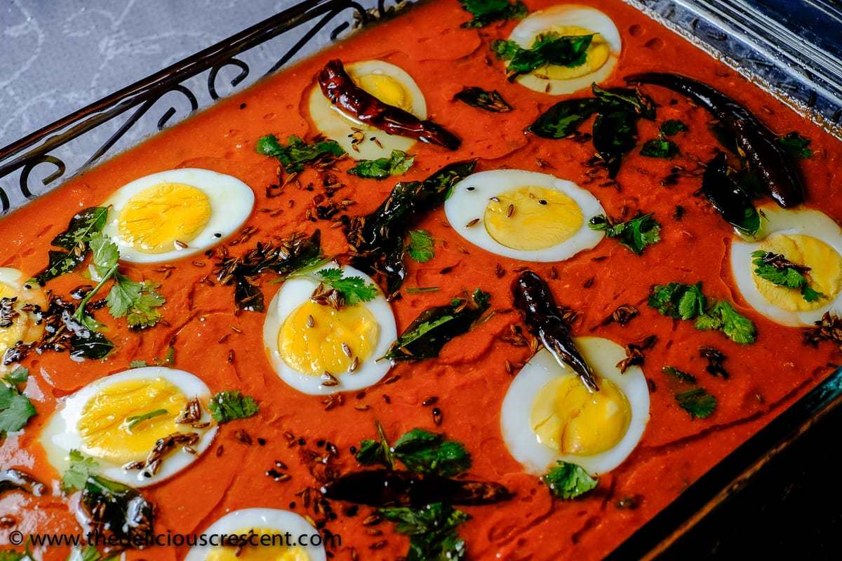 An Indian curry cooked with eggs in Hyderabadi style and served in a glass dish.