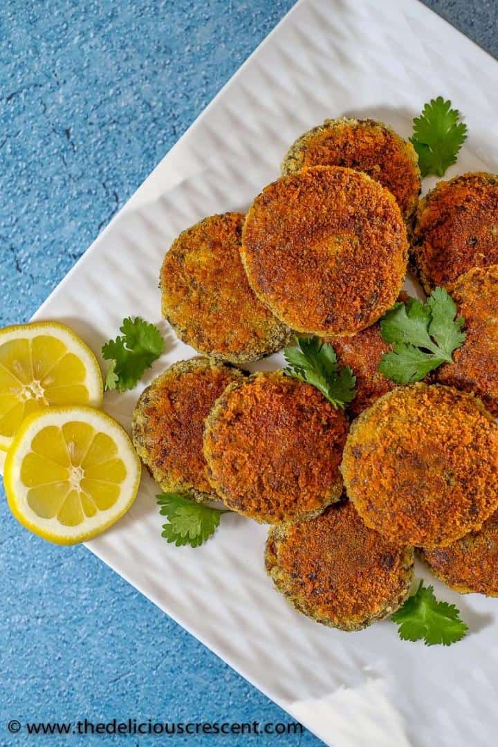 A stack of beef cutlets with lemon slices on the side.