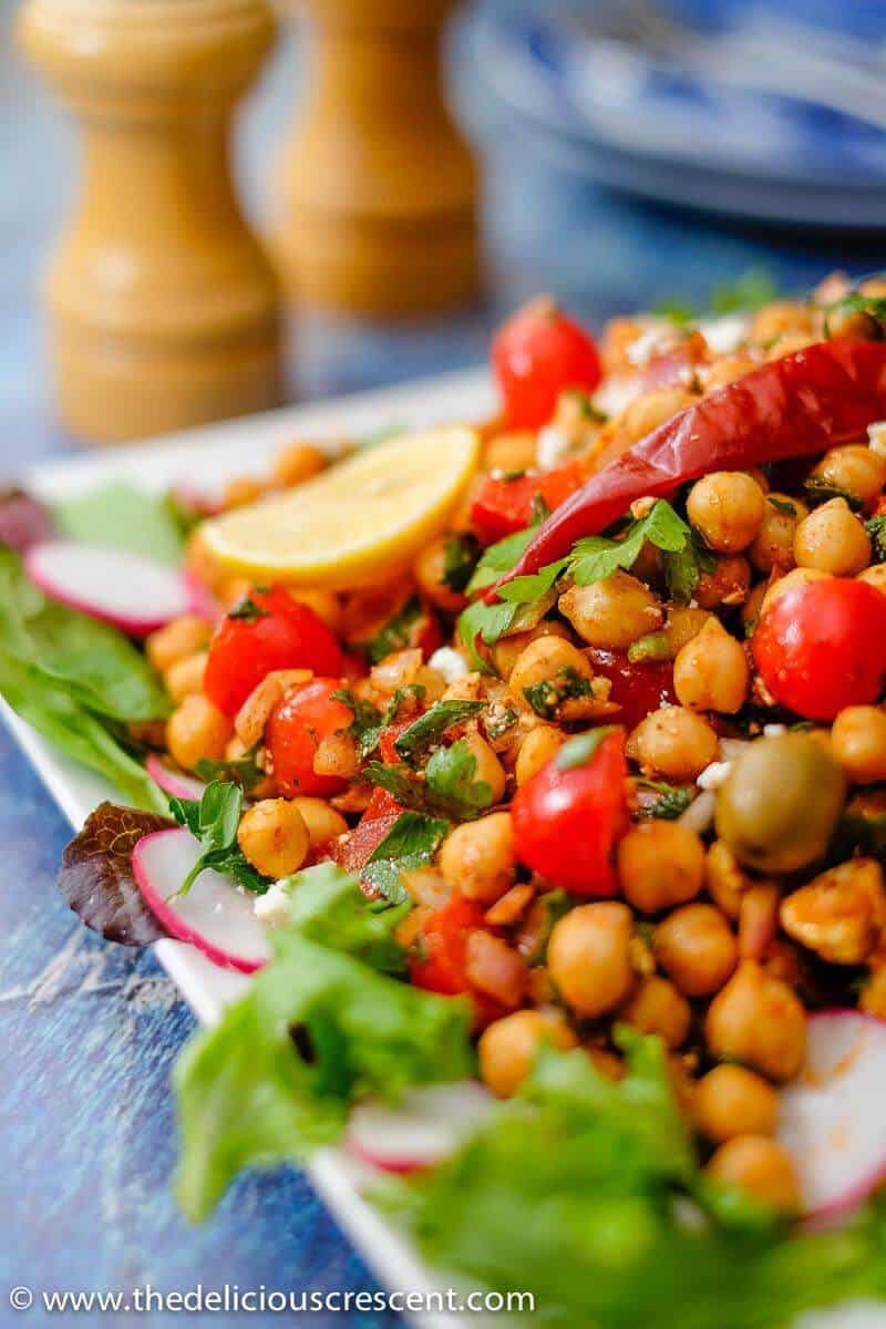 Mediterranean chickpea salad is packed with super delicious flavors and textures. It is an easy, meatless salad that is filling, healthy and packed with plant protein and fiber. Make this recipe vegan by skipping feta cheese. This simple gluten free salad with the spicy dressing will make a great meal. #chickpeasalad #Mediterraneanfood #middleeasternfood Close up view of the Mediterranean Chickpea Salad