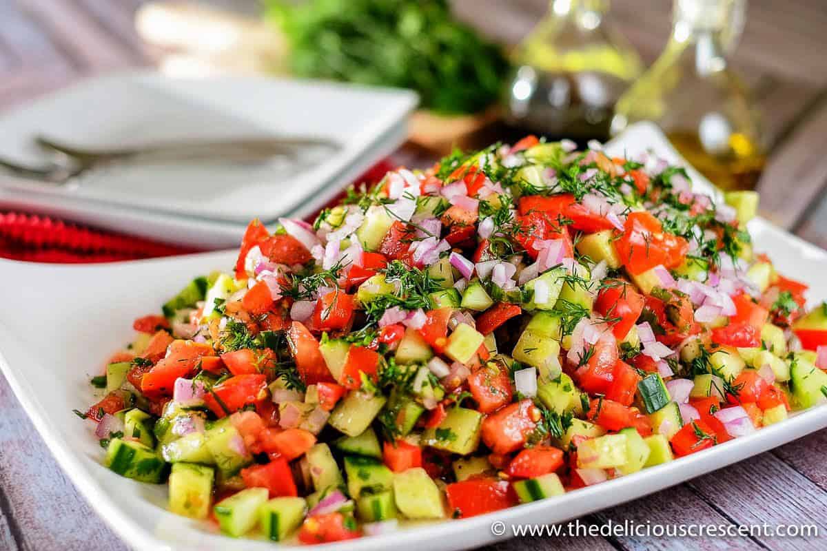 Persian tomato cucumber salad with fresh herbs served on a plate.