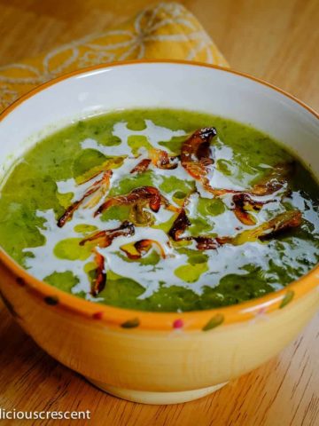 A bowl of creamy leeks avocado soup placed on the table.
