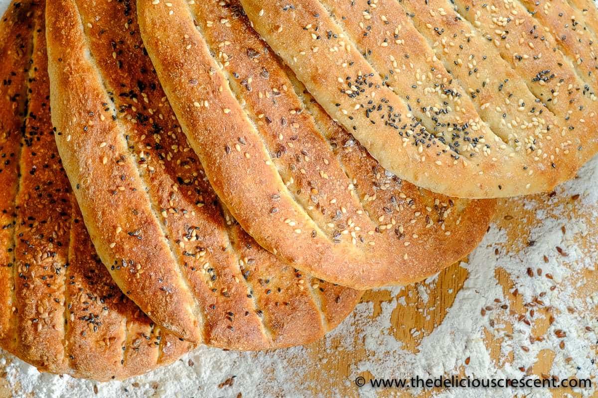 Barbari Bread is a classic Persian flatbread that is a must try for those who love baking bread. Crusty outside, tender inside and super tasty! Also known as Nan-e Barbari or Noon Barbari, this is a popular breakfast bread in Iran. It is freezer friendly and vegan. The recipe also includes tips for making it healthier. #breadrecipe #Persian #middleeasternfood Overhead view of Persian barbari bread.