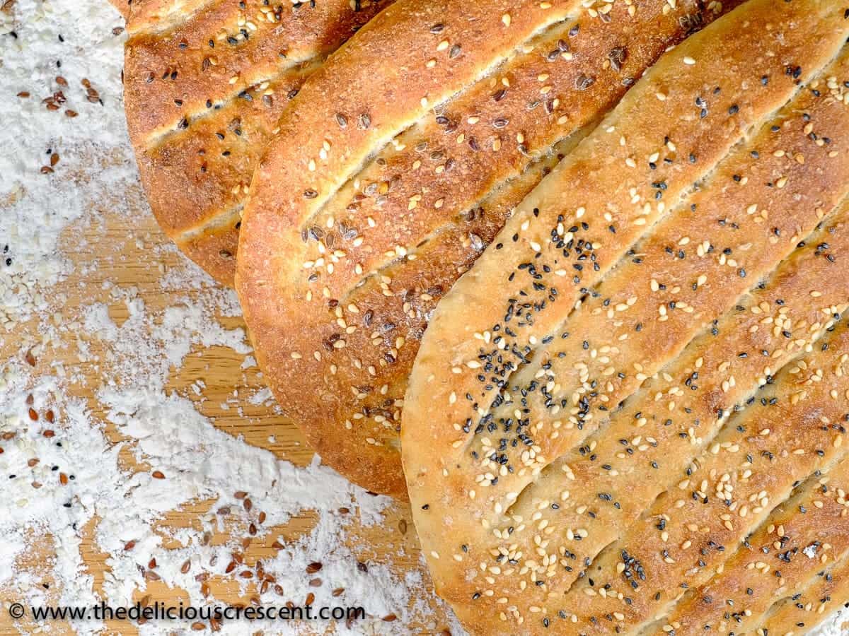 Barbari Bread is a classic Persian flatbread that is a must try for those who love baking bread. Crusty outside, tender inside and super tasty! Also known as Nan-e Barbari or Noon Barbari, this is a popular breakfast bread in Iran. It is freezer friendly and vegan. The recipe also includes tips for making it healthier. #breadrecipe #Persian #middleeasternfood Close up view of Persian flat breads, known as barbari naan.