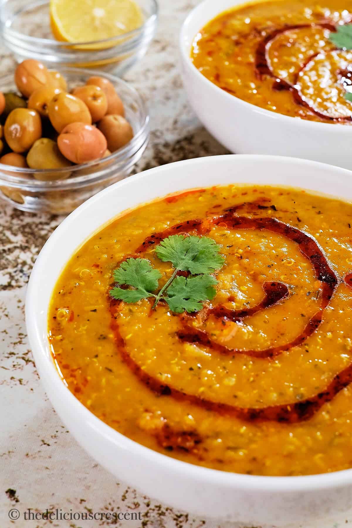 Red lentil quinoa soup served in two bowls.