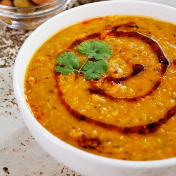 Close view of red lentil quinoa soup served in two bowls.