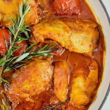 Close up view of braised tomato chicken cooked with rosemary.