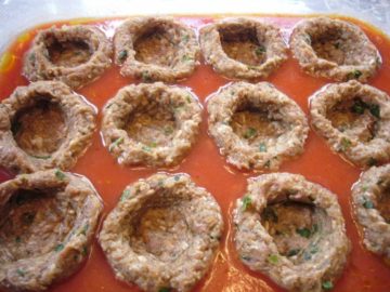 Hollowed out meatballs placed in tomato sauce for cauliflower stuffed meatballs (Pasha's kofta).