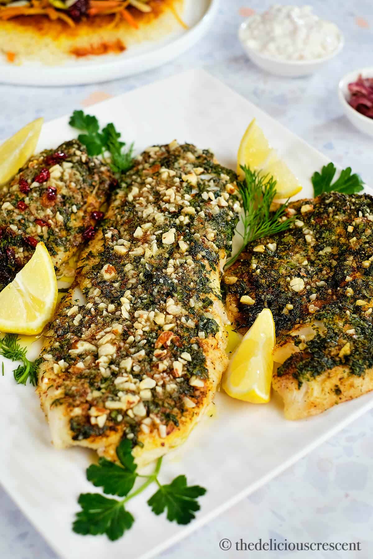 Almond crusted fish fillet in a white plate.