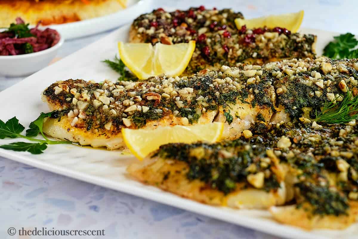 Almond crusted fish with herbs on a plate.