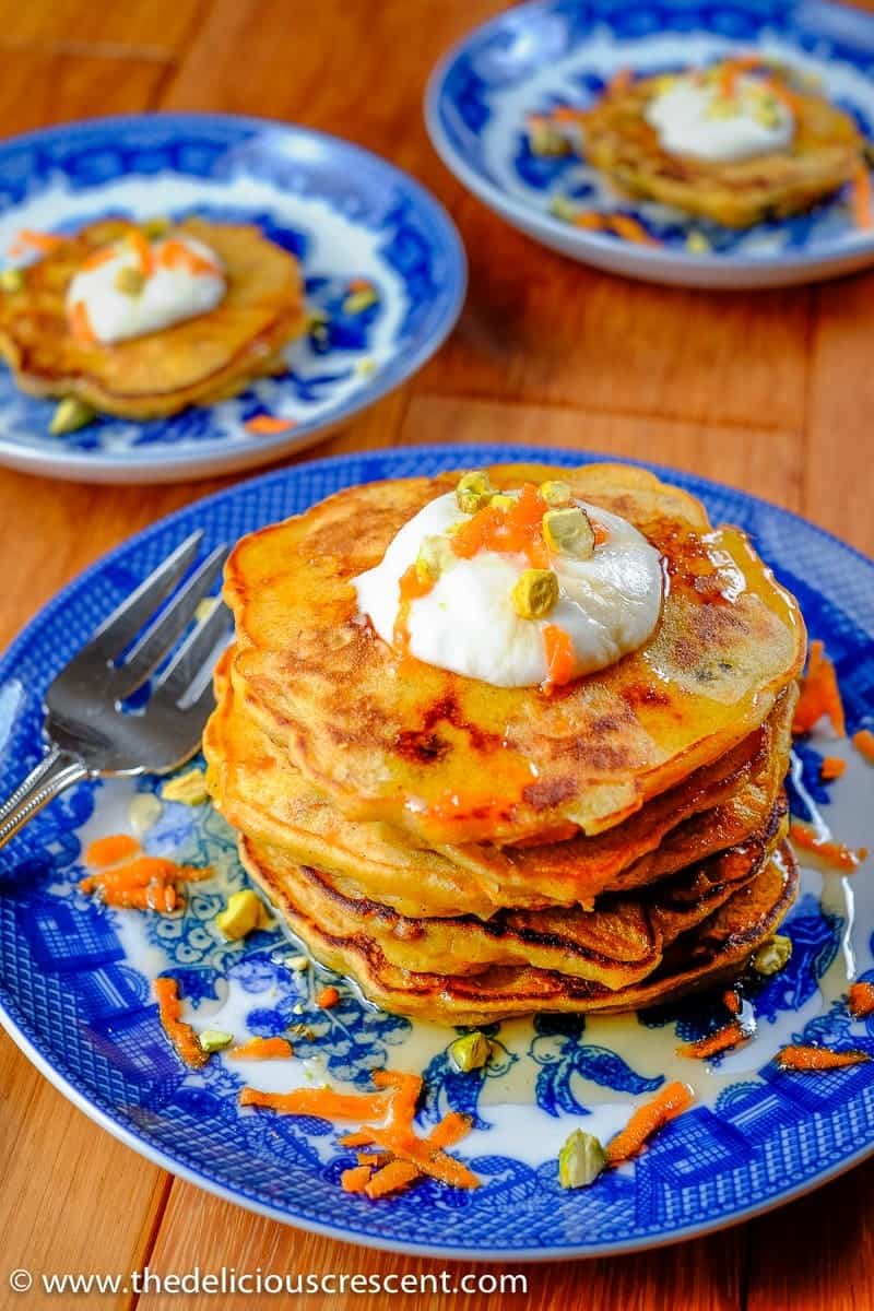 Carrot pancakes served with cream topping and maple syrup for breakfast.