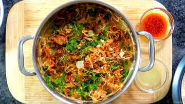 Marinated chicken topped with fried onions and herbs.