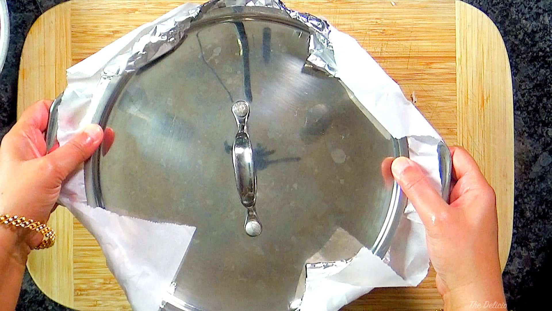 The lid placed over aluminum sheets and sealed tightly to steam the rice and chicken.