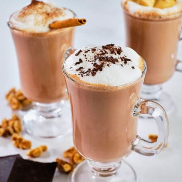 Creamy hot chocolate served in three glass mugs.