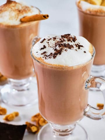 Creamy hot chocolate served in three glass mugs.