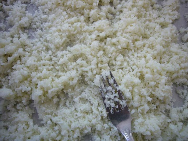 Cooled and finely processed cauliflower fluffed with a fork.