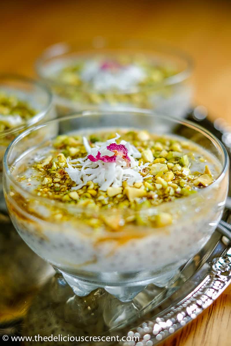 Chia mahalabia with pistachios is an Arabic style rice pudding with chia seeds added into the recipe that is fragrant with rose water. This is a creamy gluten free pudding that is healthy, easy and a quick dessert. Check out this unique chia pudding loaded with good taste, nutrition and learn about the health benefits too. #chiapudding #ricepudding. Close up view of Chia Mahalabia with Pistachios