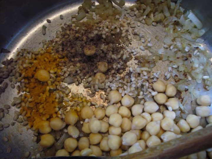 Sauteed onions with chickpeas and spices in a cooking pot.