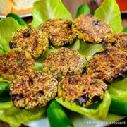 Chickpea patties with eggplant served over lettuce leaves in a plate.