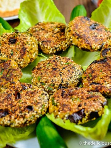 Chickpea patties with eggplant served over lettuce leaves in a plate.