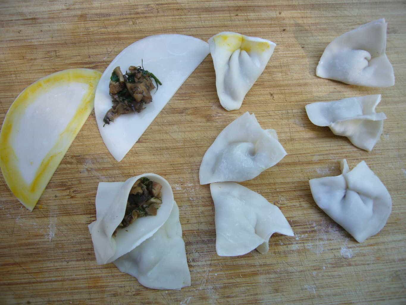 Dumpling wrappers being filled with mushroom filling.