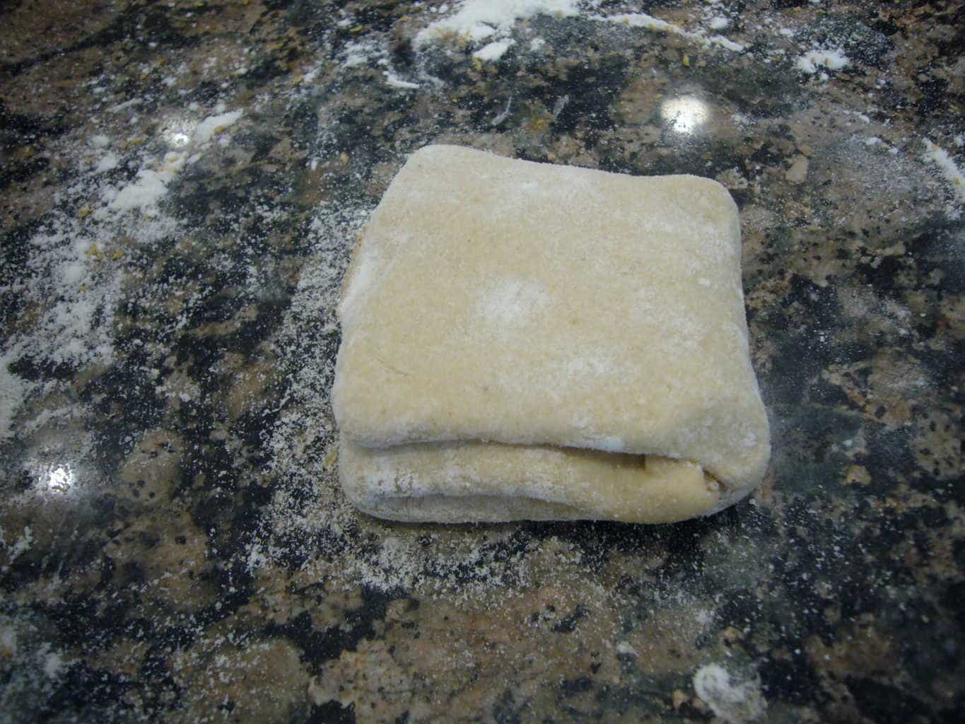 Fold over from the other side to make a square shaped layered dough portion for the egg paratha.