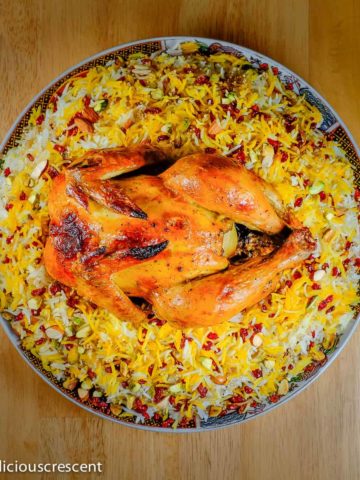 Zereshk polo ba morgh (barberry rice and saffron chicken) served on a plate.
