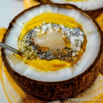 Mango smoothie topped with chia seeds and served in a coconut.