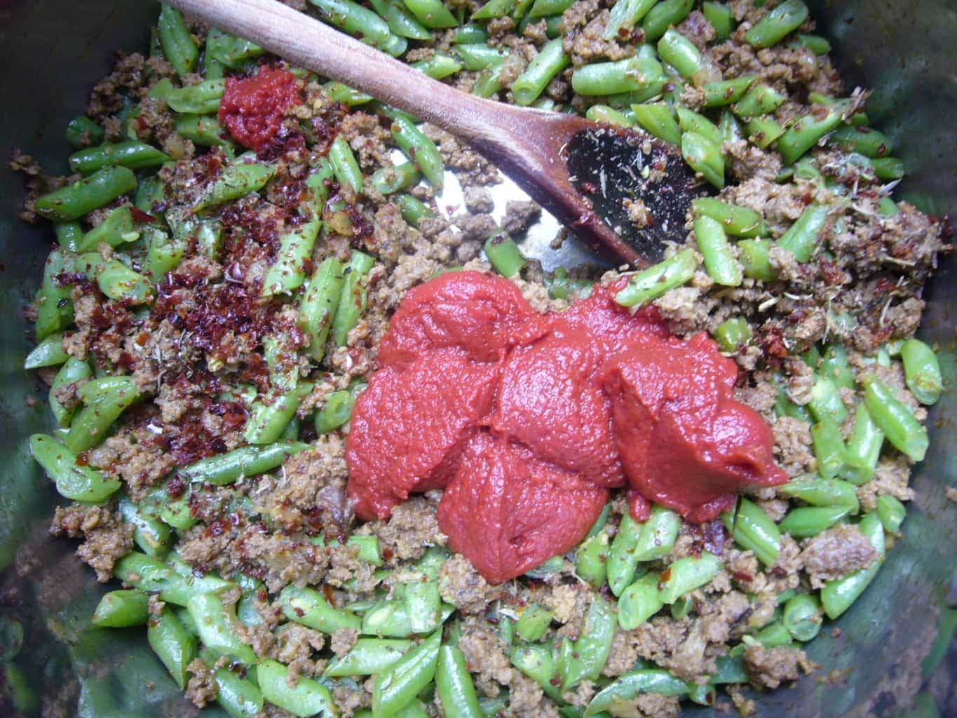 Tomato paste is added to green beans and meat to make Persian rice.