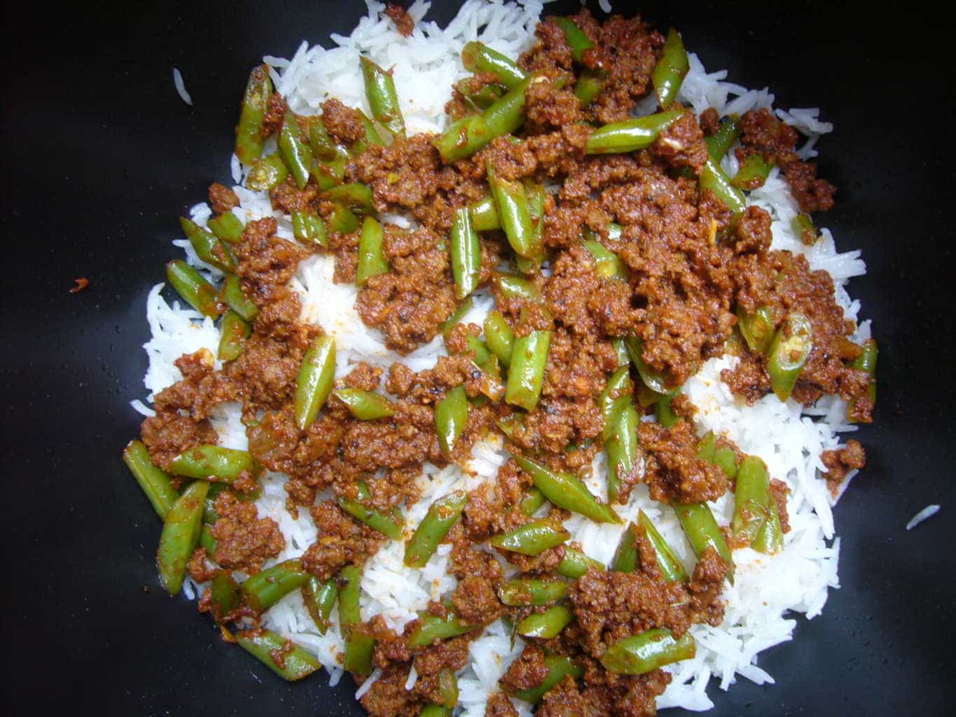 Meat and green bean mixture is layered with cooked rice to make lubia polo.