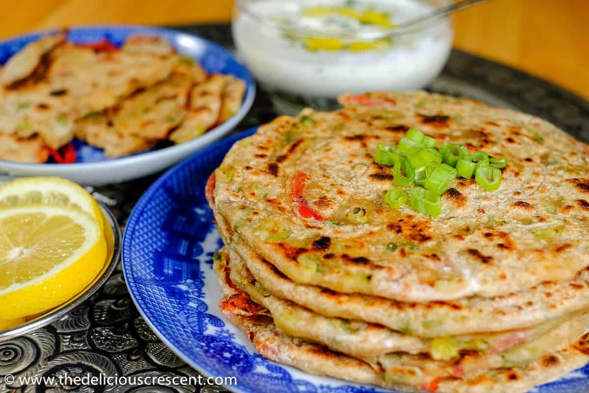 Stuffed Spring Onion Paratha is a whole grain, flavor packed, scrumptious Indian flatbread. Wholesome, with good amount of protein and fiber. Gouda Cheese, bell peppers (capsicum) and scallions come together in this wonderful and easy flatbread. Pair it with a Walnut Chutney or a Greek yogurt dip with grated garlic and dill for a splendid nutritious meal!