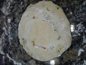Stuffed parathas rolled on a granite stone.