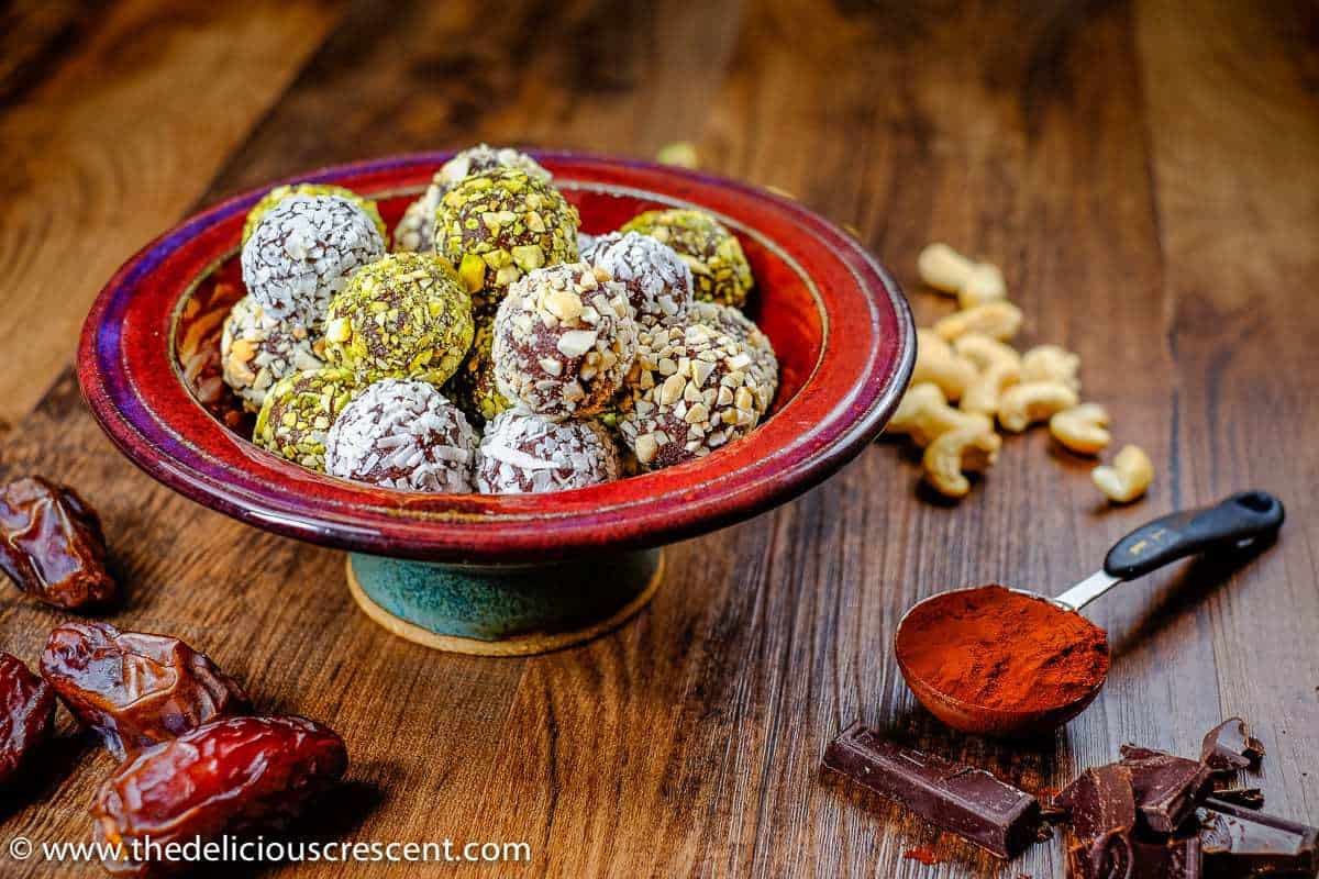 Dark chocolate date avocado truffles are a melt-in-your-mouth treat. These easy, healthy, low carb, gluten free homemade truffles are made without heavy cream or butter. They are sweetened with dates and have minimal added sugar and saturated fat. A great chocolate dessert snack for holidays! Vegan and dairy free options. #truffles #healthysnacks #chocolaterecipes Luscious Date Avocado Chocolate Truffles in a serving bowl.