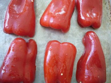 Red bell peppers placed on a baking sheet.