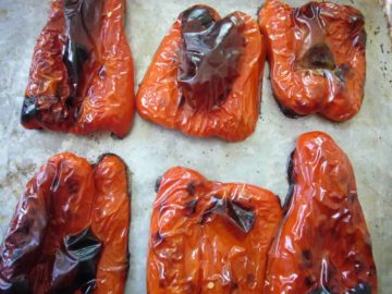Roasted red bell peppers on a baking sheet.