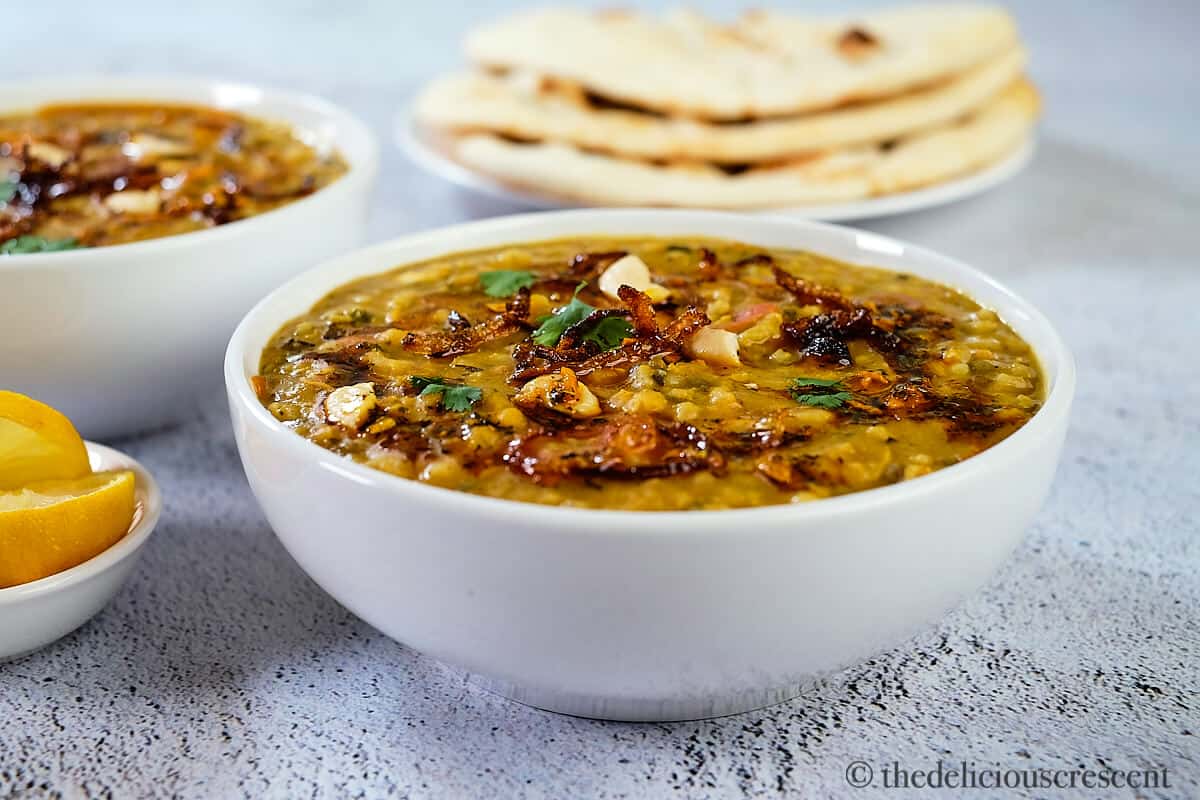 Bowls of chicken khichda with naan on a table.