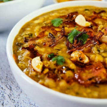 Close view of chicken khichda served in a white bowl and placed on the table.