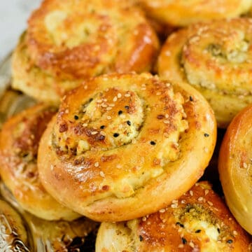 Close view of zaatar bread rolls stacked on a plate.