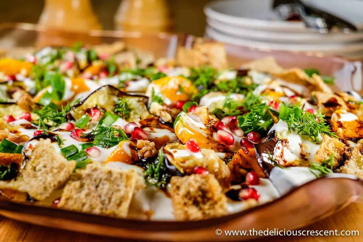 Eggplant Yogurt Salad, an adapted version of the popular dish "Fatteh" with added butternut squash. It is so tasty with roasted vegetables in creamy yogurt sauce with crunchy pomegranate, walnuts and crispy pita chips.
