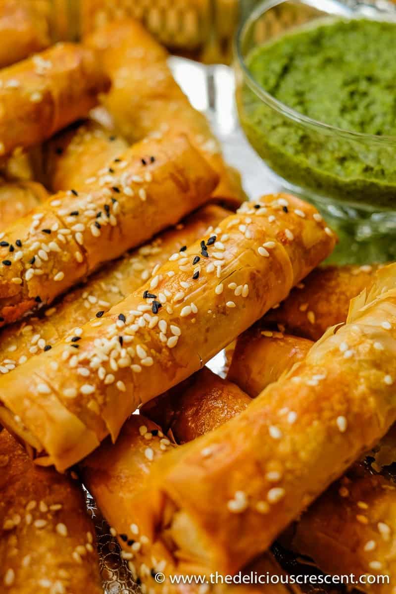 Close view of phyllo dough samosas served with green chutney.