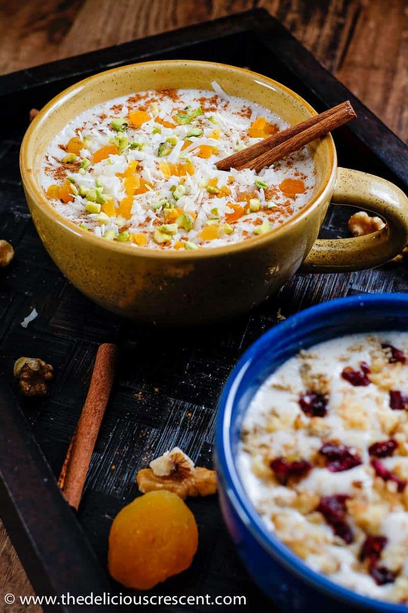 Overhead view of sahlab topped with dried fruit and served in two cups.