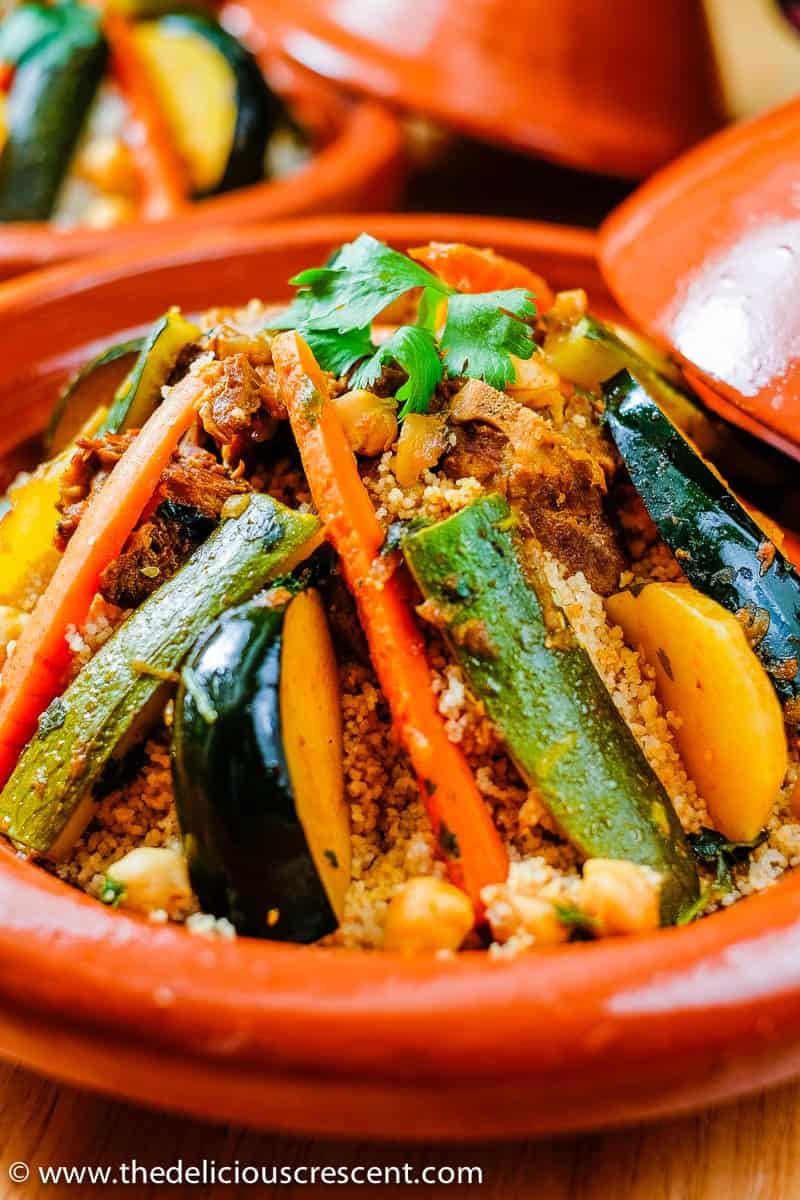 Moroccan stew with lamb and assorted vegetables served over couscous in a tagine.