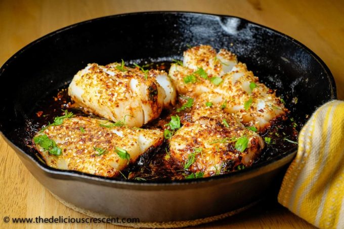 Tamarind fish seared in a cast iron skillet and topped with herbs.