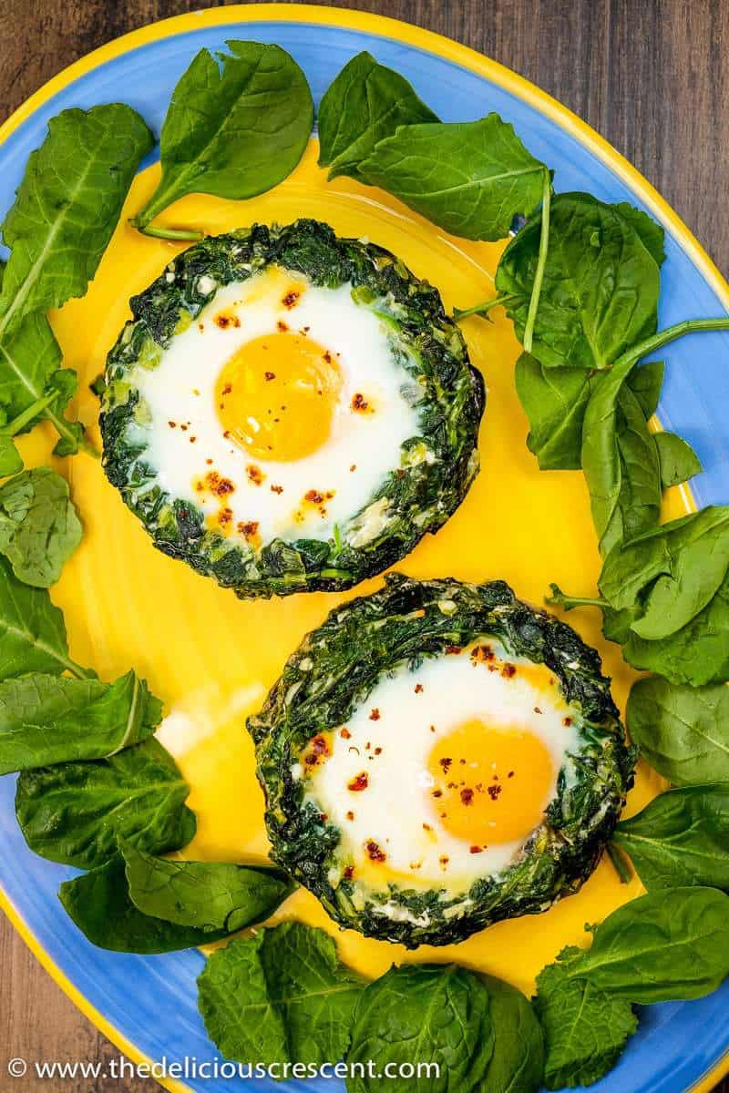 Spinach egg stuffed portobello mushrooms placed on a yellow serving plate.