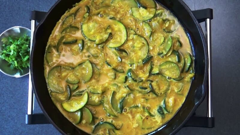 Spice-egg mixture being combined with the sauteed zucchini for frittata.