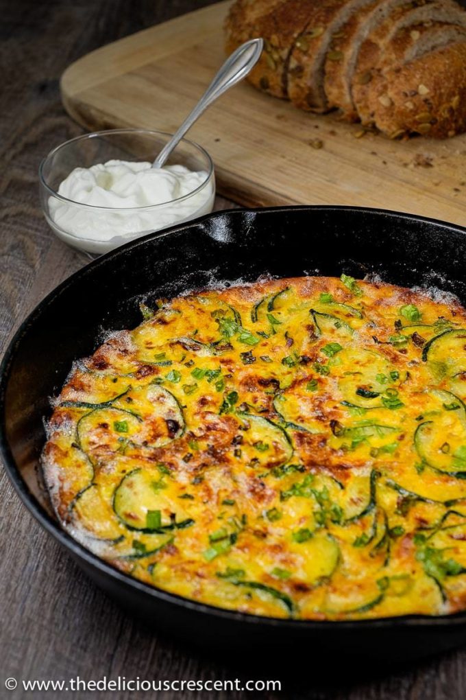 Persian zucchini frittata baked in a cast iron skillet and placed on a table.