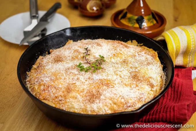 Moroccan chicken pie baked in a cast iron skillet and served on the table.