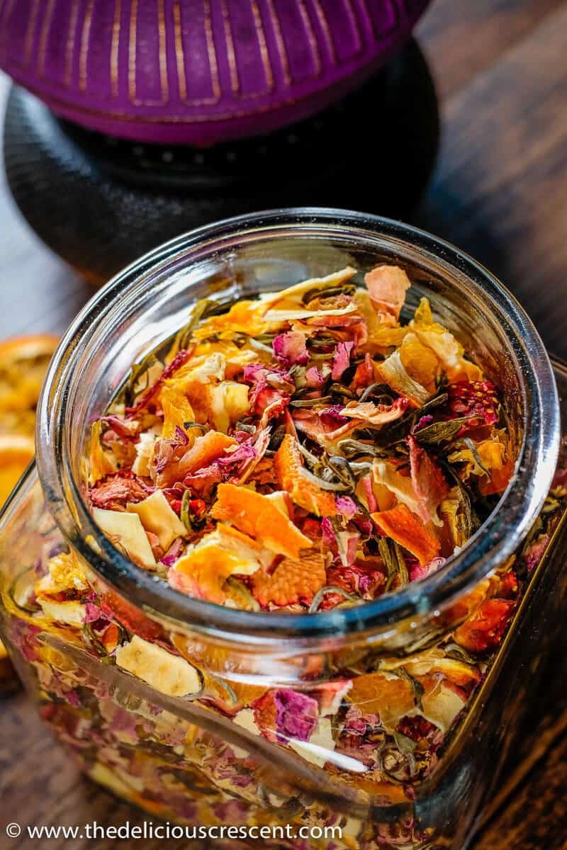 Homemade tea blend with citrus, berries, apples, roses and white tea is an invigorating infusion of sweet fruit flavors and the lively taste of antioxidant rich white tea. It is a quick and easy to make gluten free tea beverage. This healthy tea blend recipe is suitable for vegan, vegetarian and low carb diets. #homemade #tea Overhead view of a homemade tea blend made with dried roses, citrus, berries, and apples.