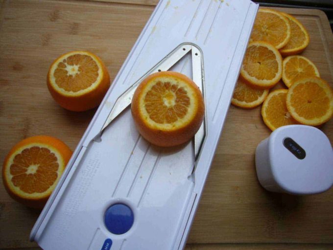 Oranges being sliced using a mandolin slicer to be dried for making a homemade tea blend.